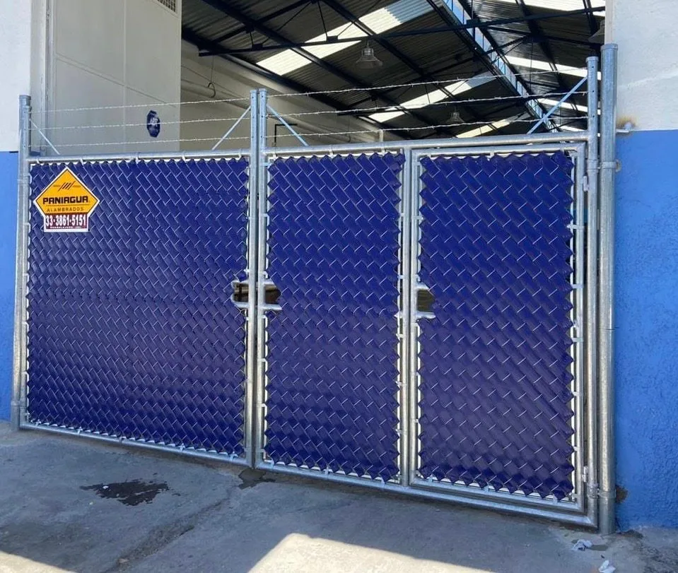 Portón de malla con cinta de privacidad azul dentro de una bodega