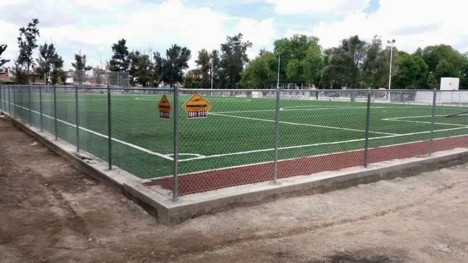 Malla ciclónica con placas Paniagua alrededor de una cancha de pasto sintético